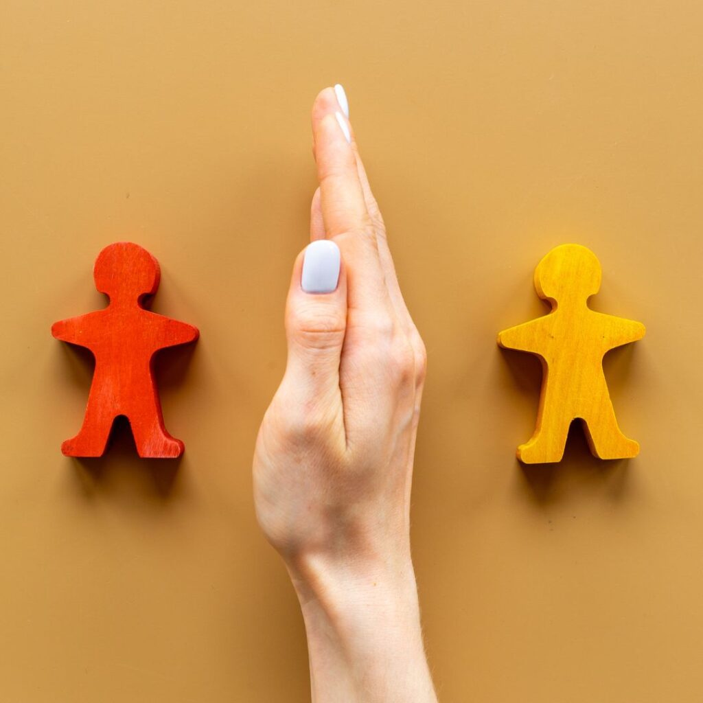 Hand between two wooden people
