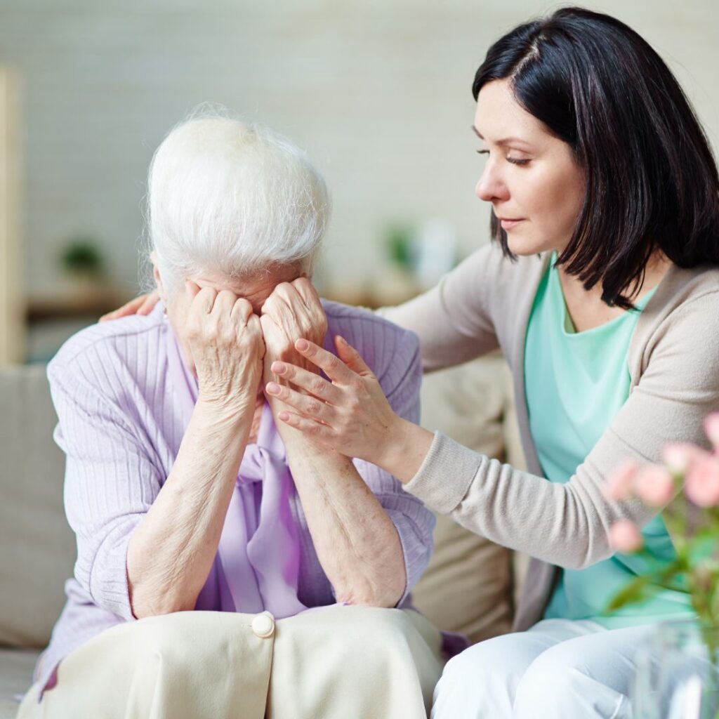 Elderly woman experiencing grief and being supported by younger woman
