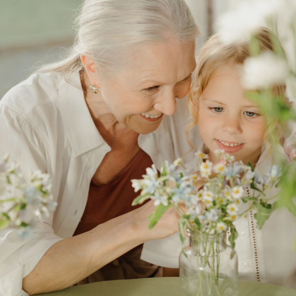 Elderly woman showing young child flowers
