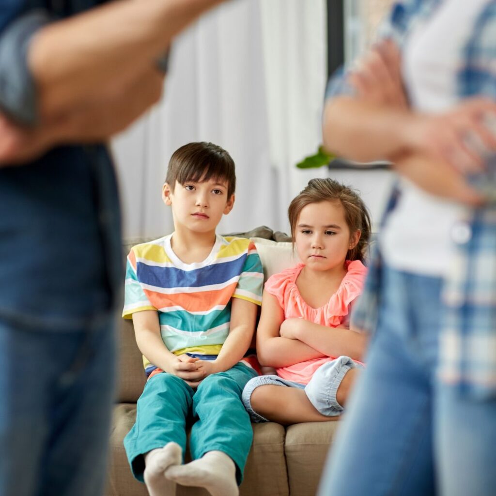 Children sitting on couch while parents are arguing